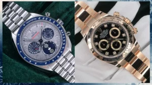 Side-by-side Omega Speedmaster Moonphase and Rolex Daytona on green velvet, showing dials and bezels.