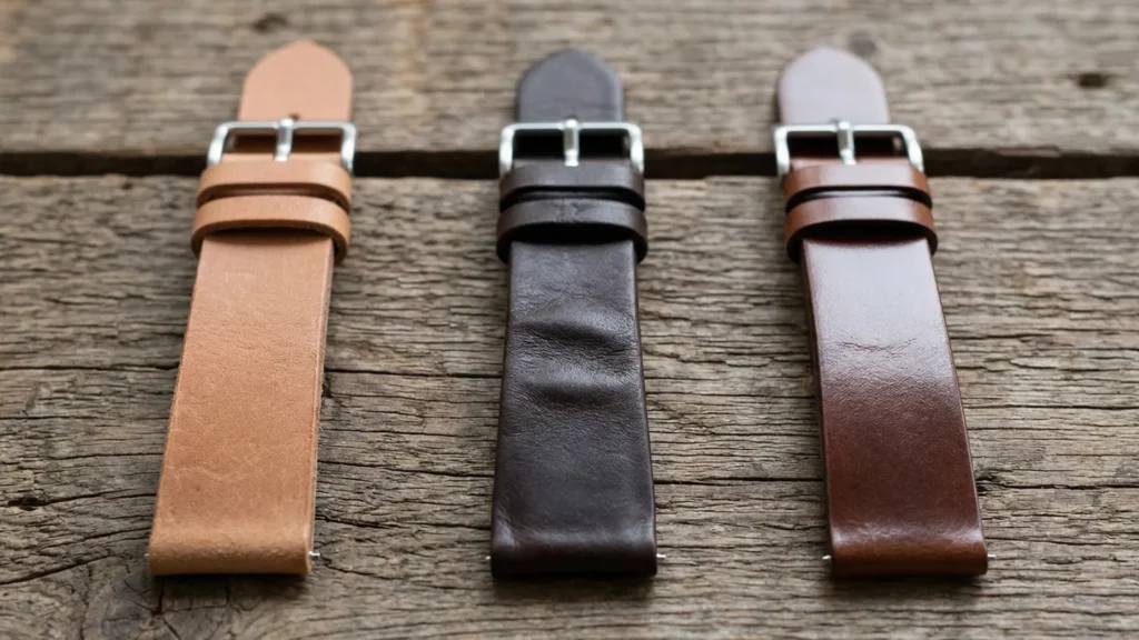 Tan perforated pigskin leather racing strap on white dial field watch on concrete surface