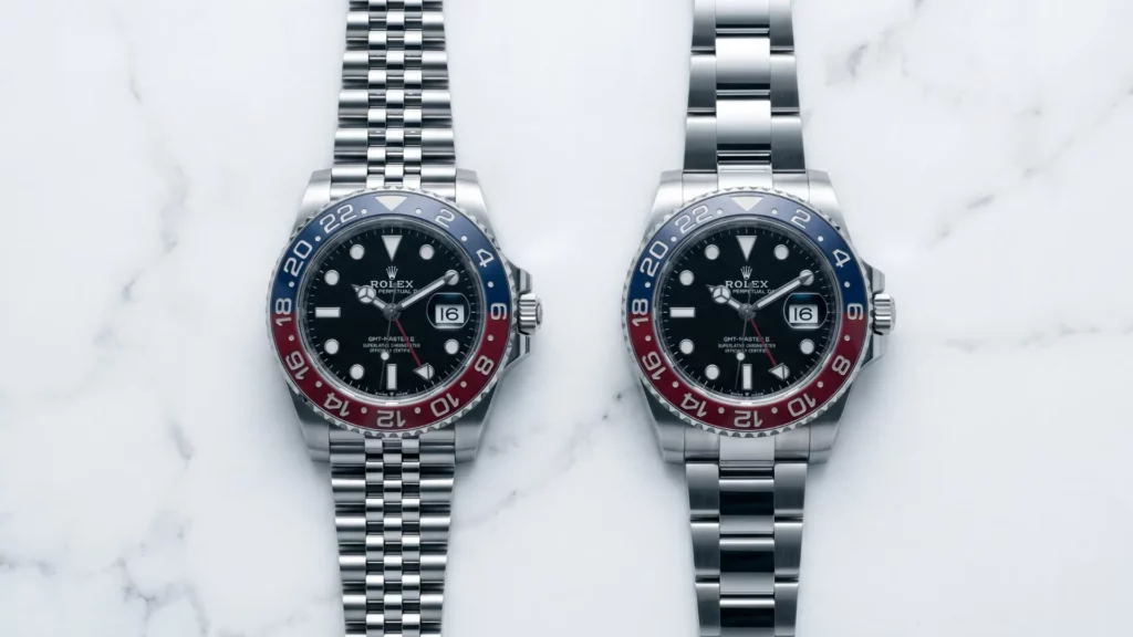 Rolex GMT-Master II Pepsi on five-link jubilee bracelet next to same model on three-link Oyster bracelet on marble surface