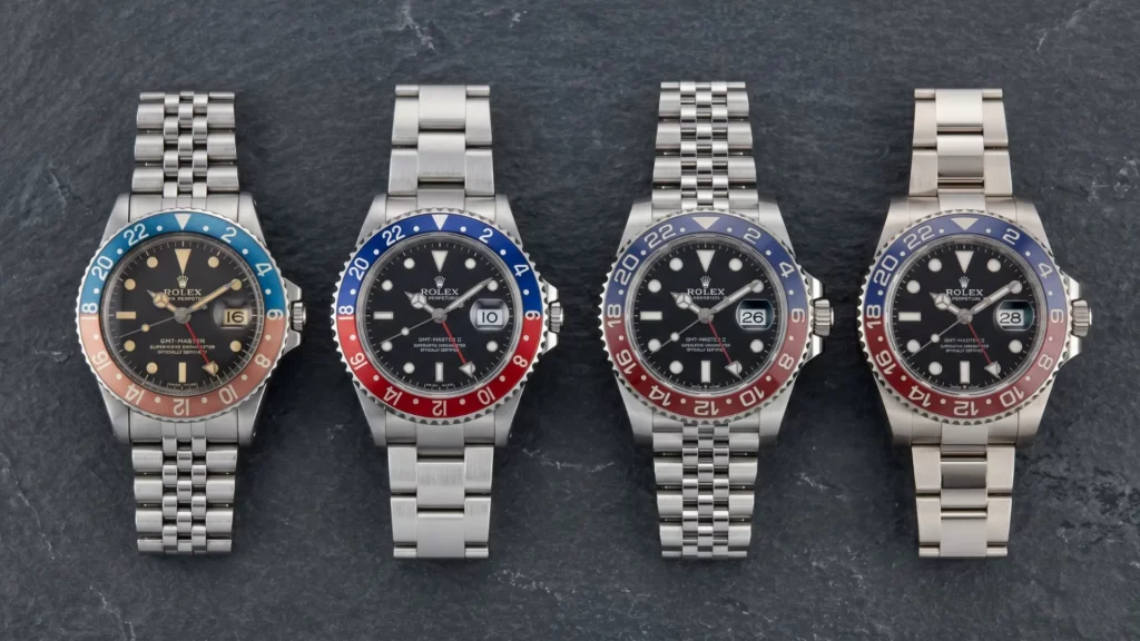 Four Rolex Pepsi GMT-Master references from vintage to modern laid side by side on slate surface showing bezel and bracelet evolution