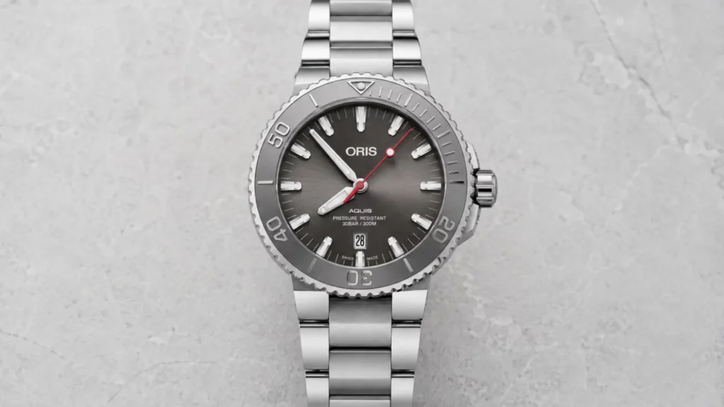 Oris Aquis Date grey dial watch on steel bracelet against light stone