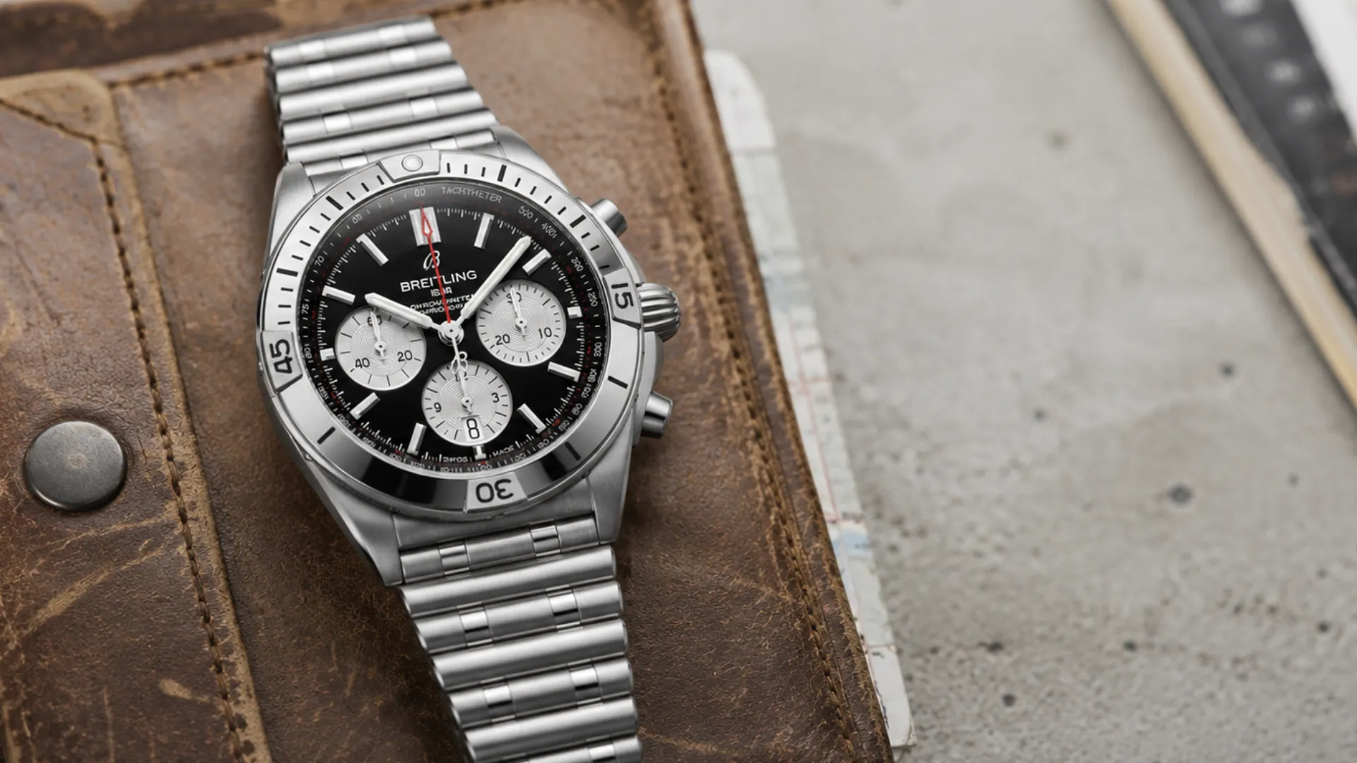 Breitling Chronomat chronograph on steel bracelet against leather and desk accessories