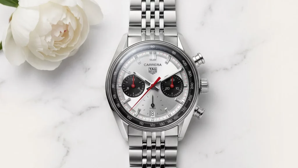 TAG Heuer Carrera panda chronograph on steel bracelet beside white flower