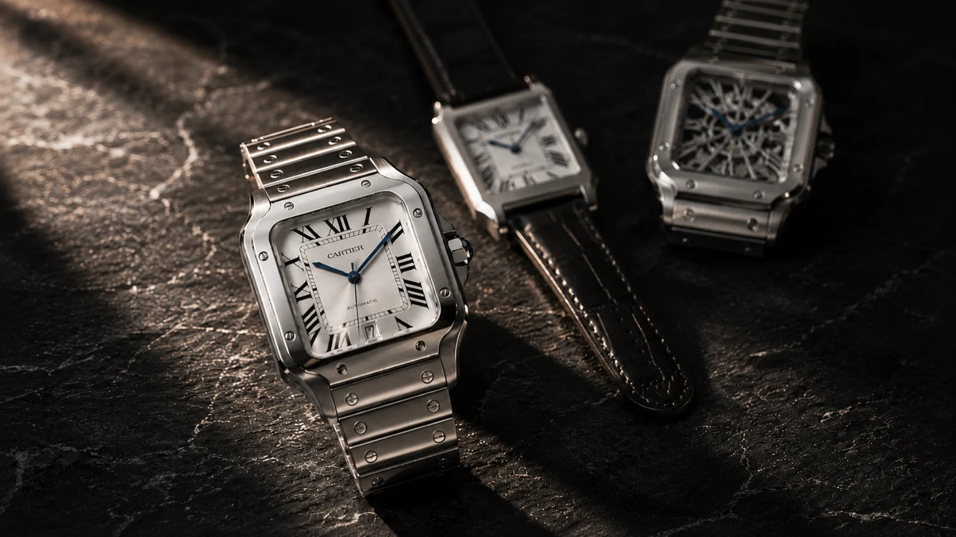 Cartier Santos watch in stainless steel on a dark stone surface with two blurred Cartier-style watches in the background.