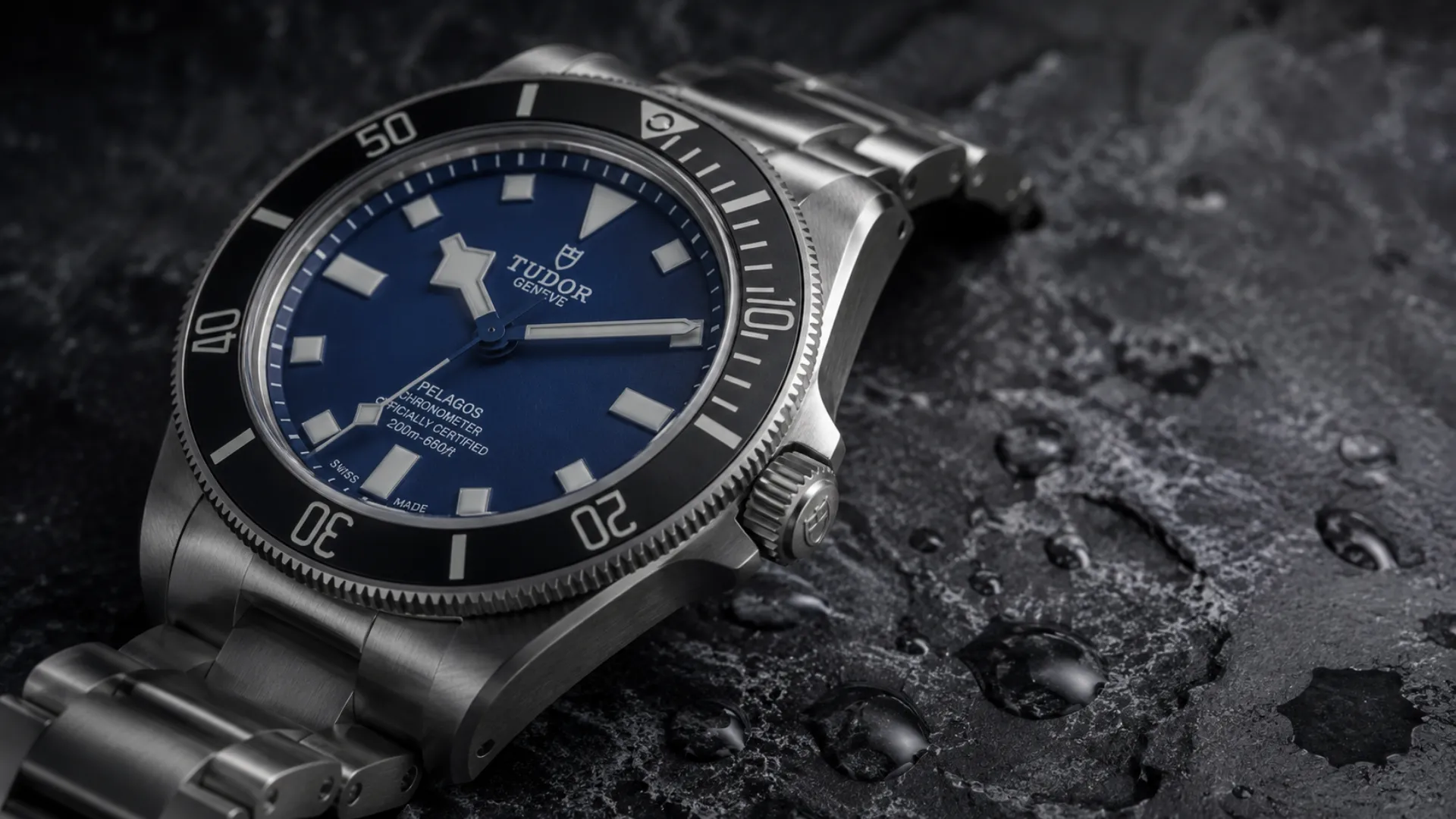Tudor Pelagos with blue dial and titanium bracelet on a dark wet stone surface