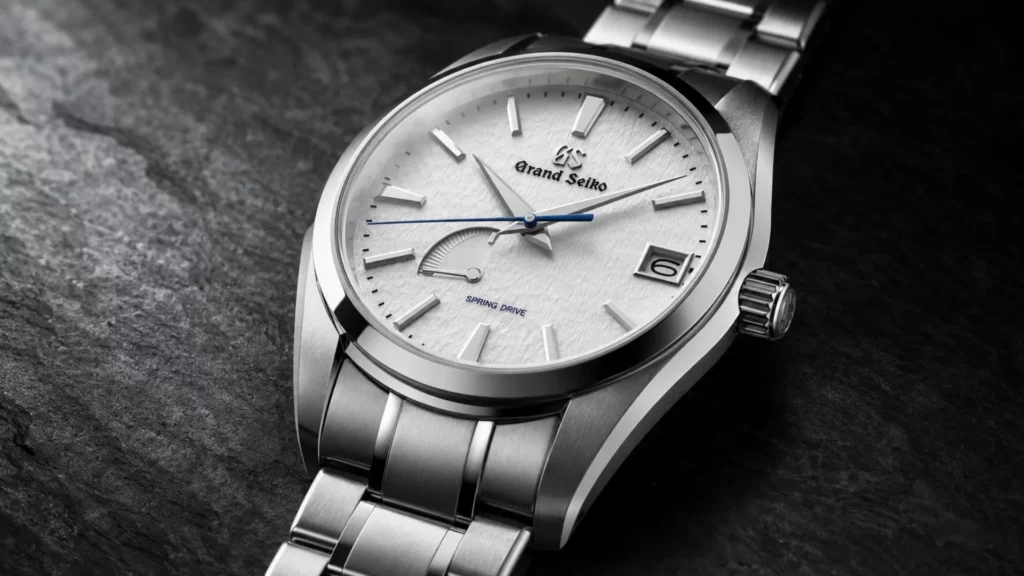 Grand Seiko Snowflake SBGA211 with textured white dial and titanium bracelet on dark slate background