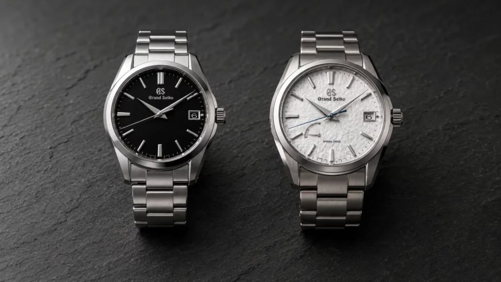Two Grand Seiko watches on a dark slate surface, black and white dials
