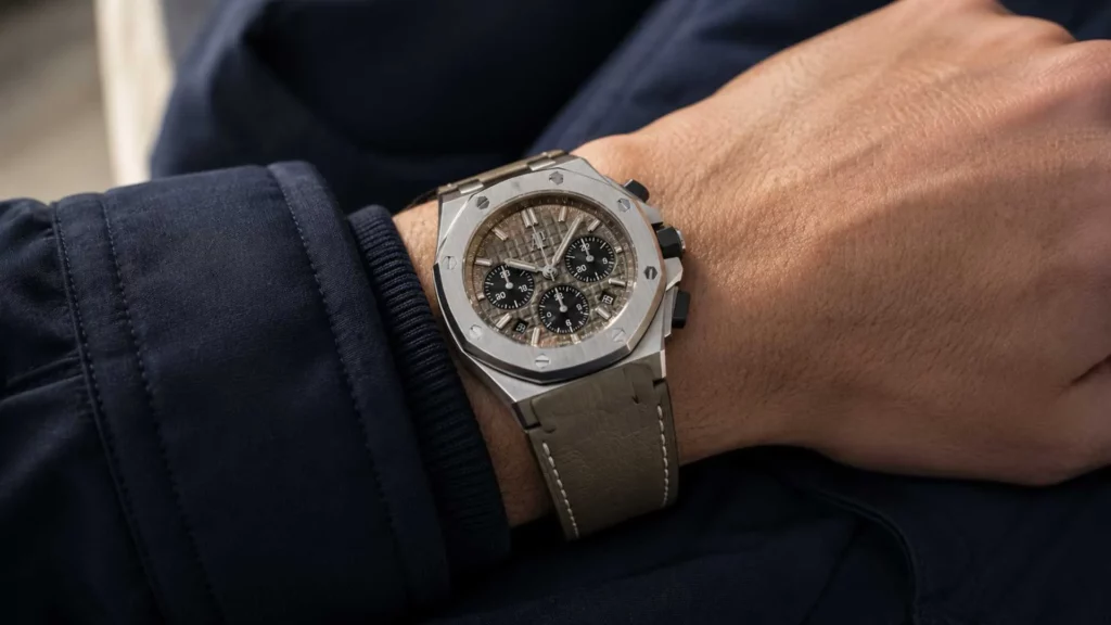  Taupe leather watch strap on a stainless steel sport watch worn against a navy jacket cuf
