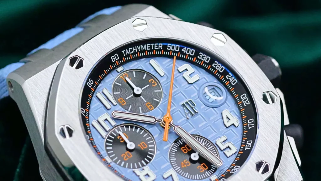 Close-up of an Audemars Piguet Royal Oak Offshore Chronograph with a baby blue dial, orange chronograph hand, stainless steel octagonal bezel, and blue rubber strap.