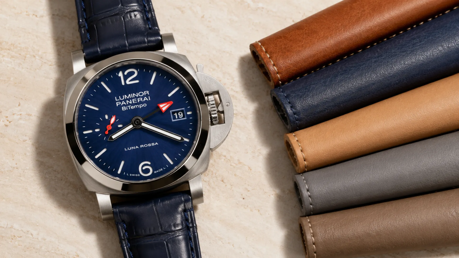 Panerai Luminor BiTempo with blue sunburst dial on a navy alligator strap beside a fanned row of tan, navy, camel, grey, and taupe leather straps