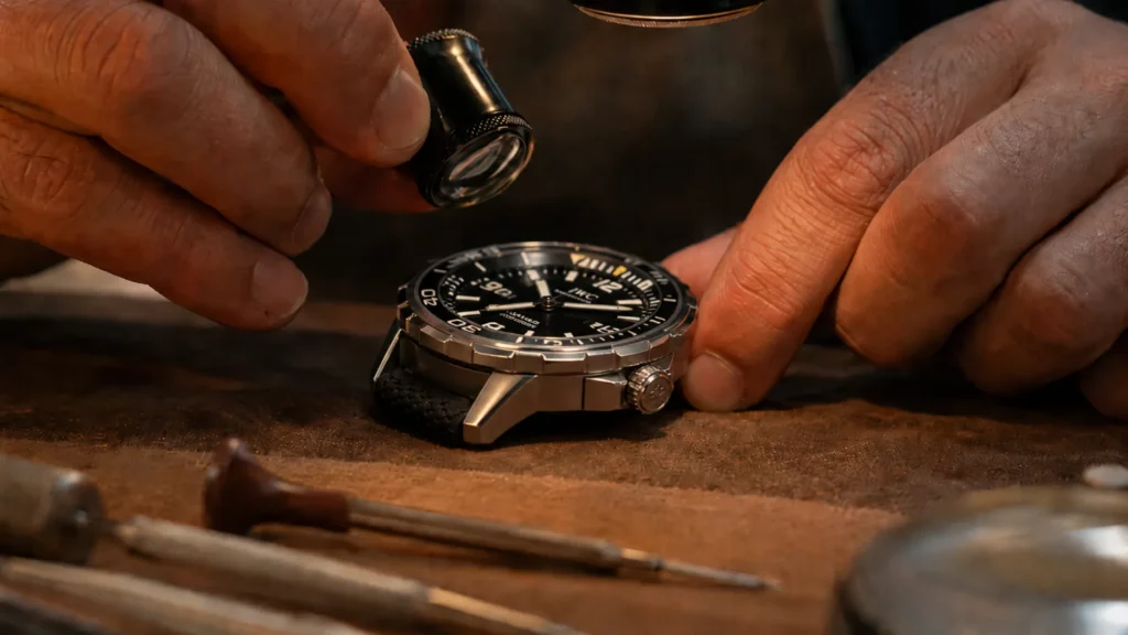 Dealer inspecting a pre-owned IWC Aquatimer under a loupe to check case and coating condition