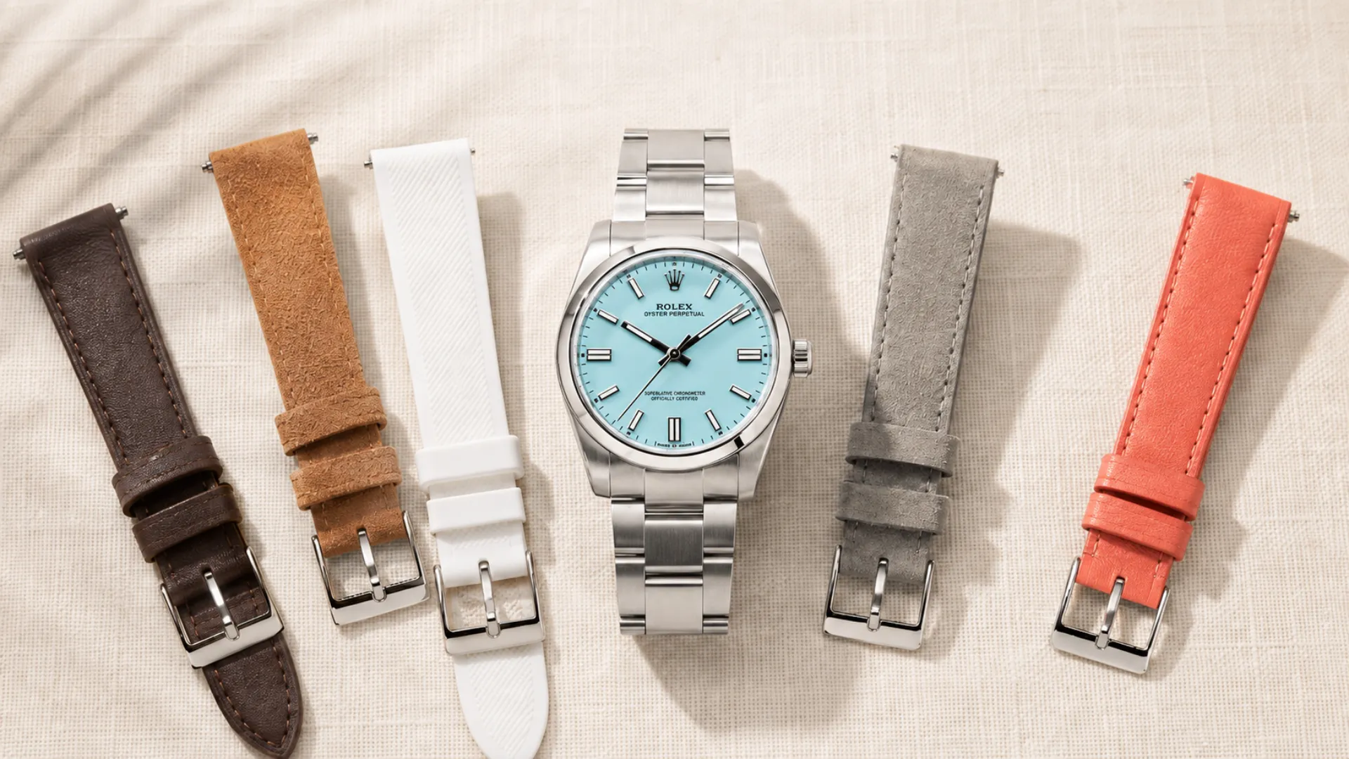 Turquoise dial watch surrounded by brown, tan, white and coral strap options for pairing