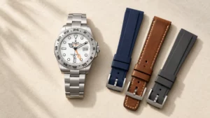 Orange accent dial watch shown with navy, cognac, and charcoal strap options laid beside it