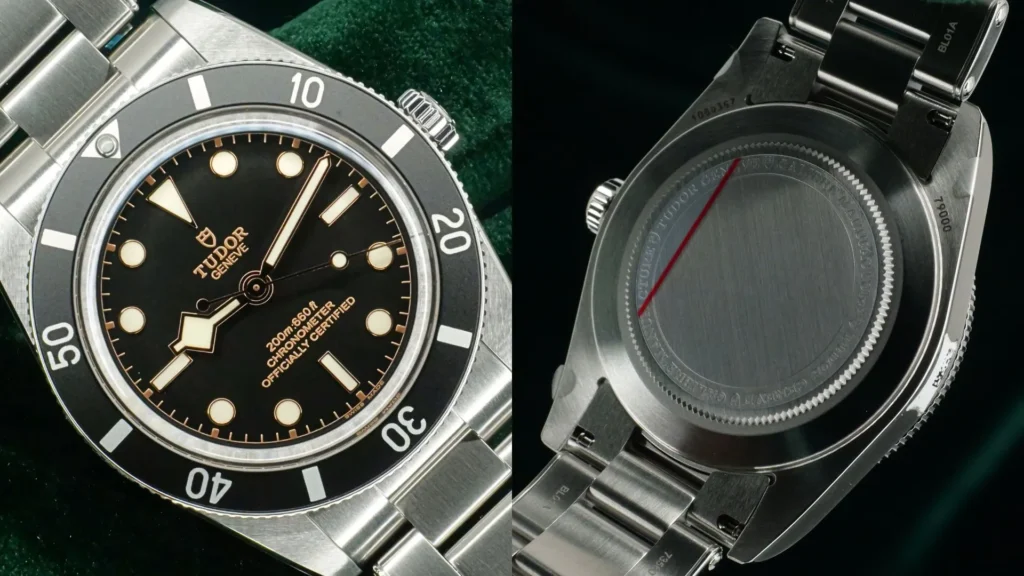 Steel Tudor Black Bay 54 with black dial and gilt accents beside its engraved caseback on green velvet
